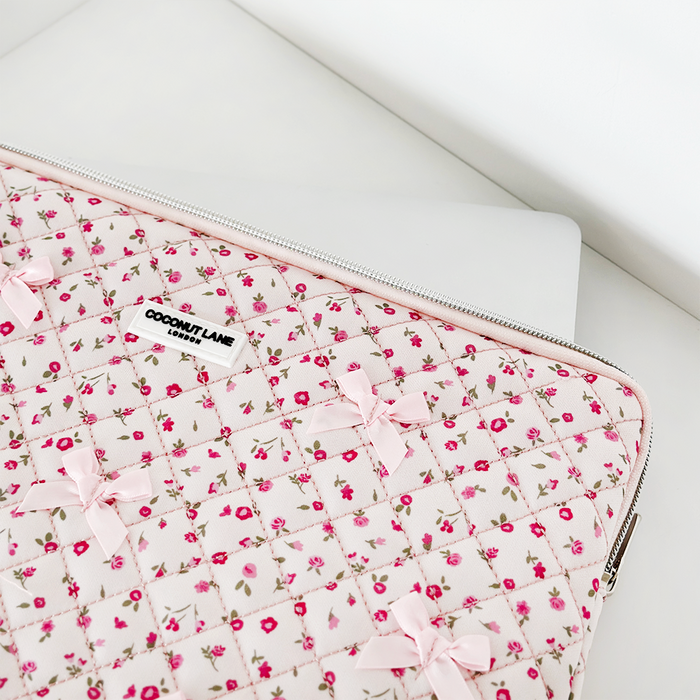 Silver laptop partly inside a pink quilted laptop sleeve with watercolor flower design.