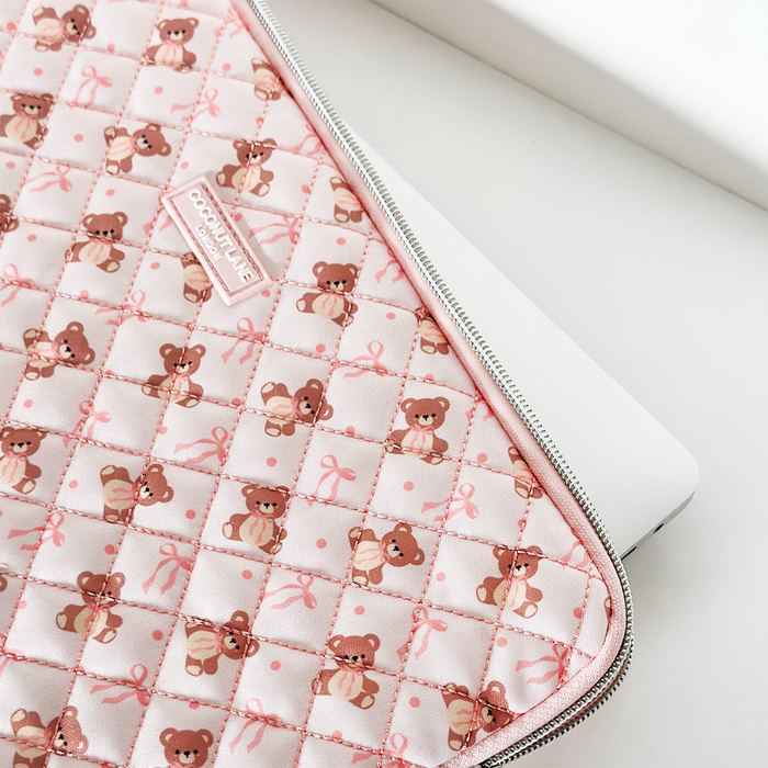 Pink quilted laptop sleeve with bow pattern and teddy finish, partially open to reveal a laptop inside.