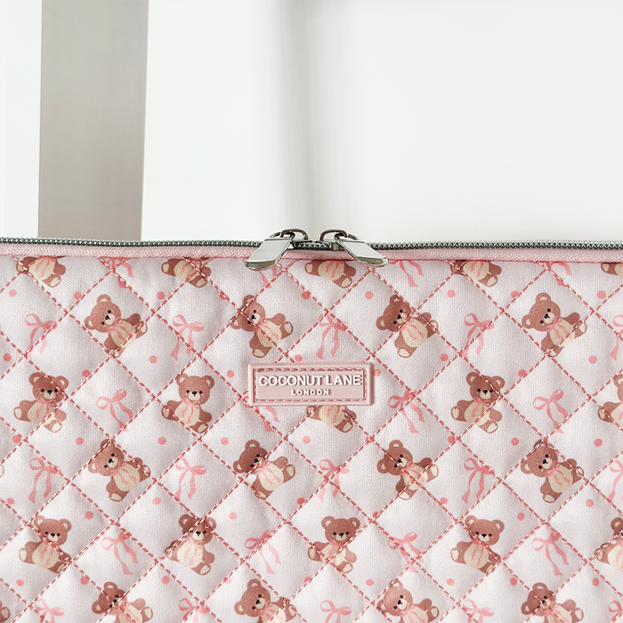 Pink quilted laptop sleeve with teddy bear and bow pattern, finished with a silver zipper.