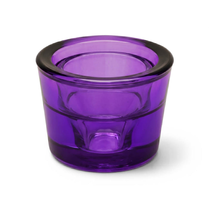 Empty purple glass votive holder on a white background