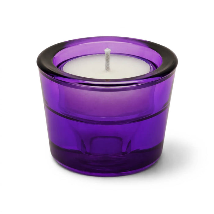 White tea light candle in a purple glass holder on a white background
