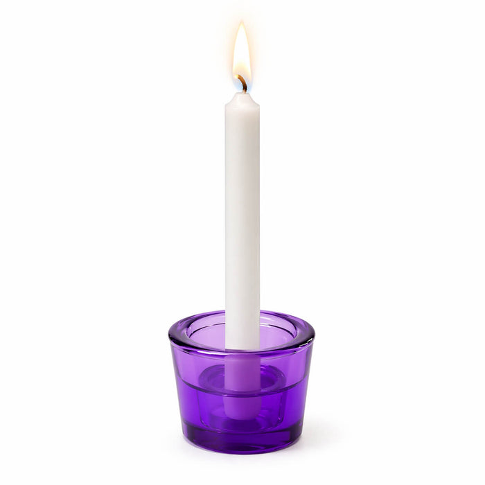 Lit white taper candle in a purple glass holder
