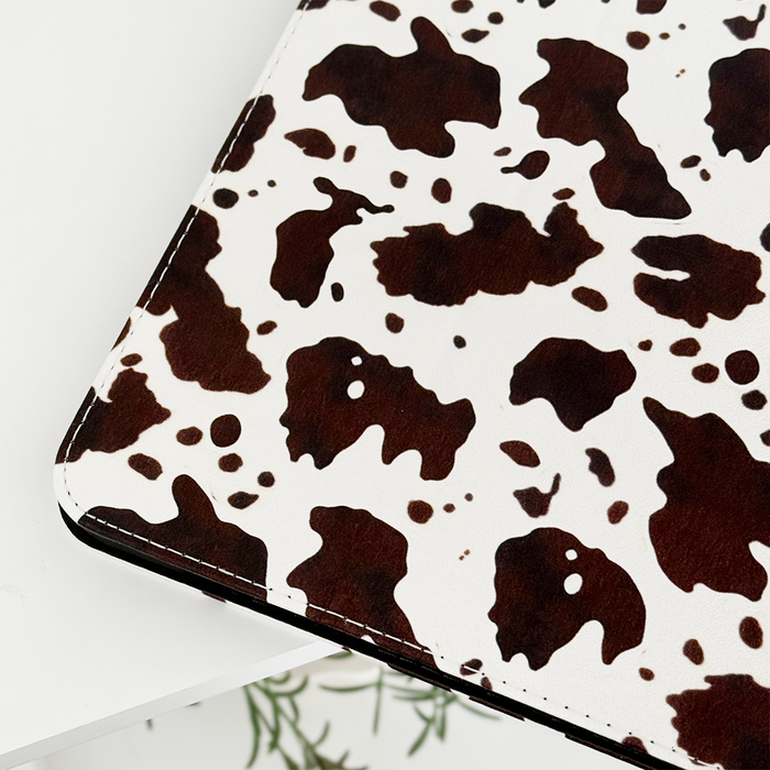 Rodeo Cowgirl iPad Case by Coconut Lane, close-up on white surface with green plant leaves partially visible below.