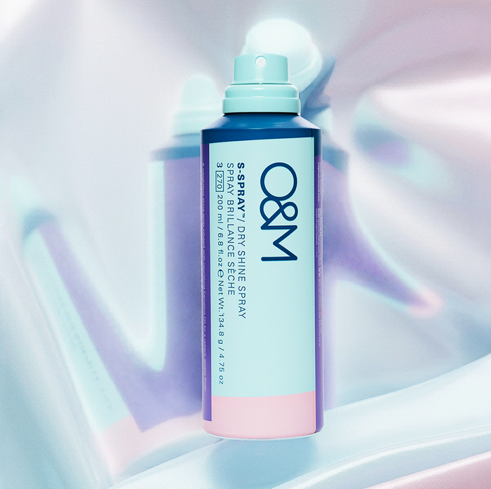 O&M dry shine spray bottle on a colorful abstract background