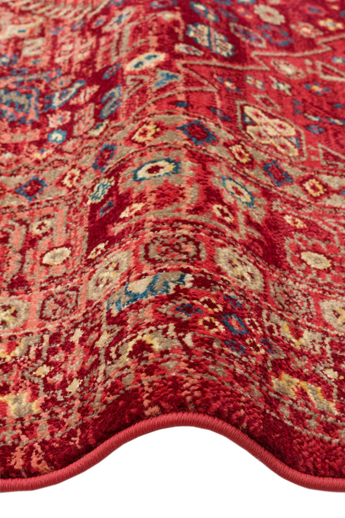 Red traditional rug with a distressed Persian-style pattern in blue, beige, and yellow accents.