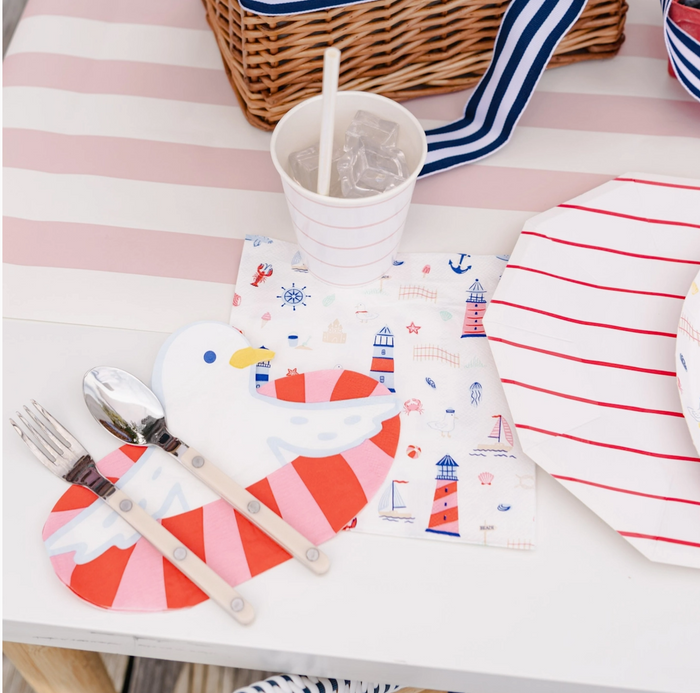 Children's tableware set with red and white striped plate, cup, and cutlery on a striped tablecloth.