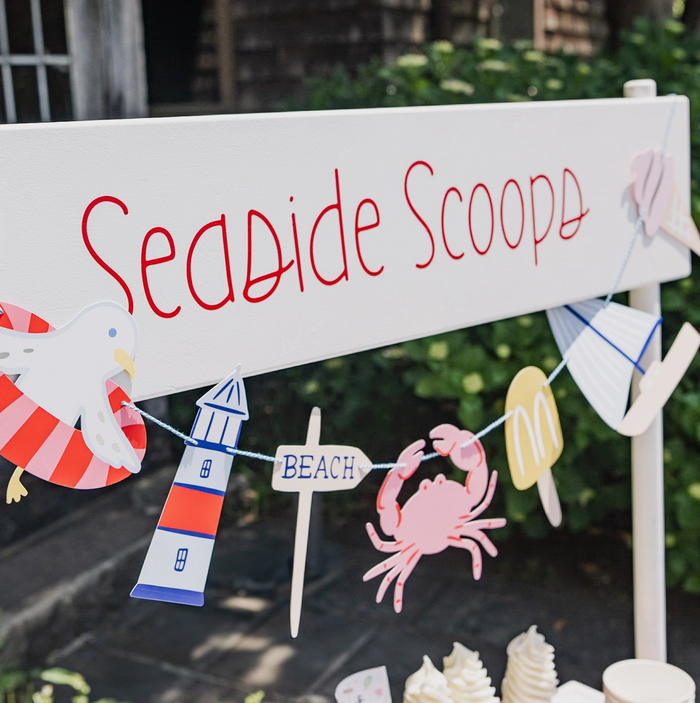 Decorative sign with 'Seaside Scoops' and beach-themed decorations on a stand.