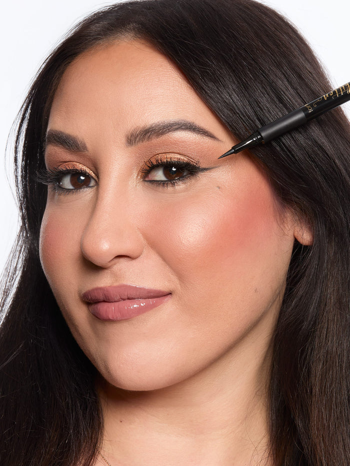 Woman applying eyeliner with a brush on a white background