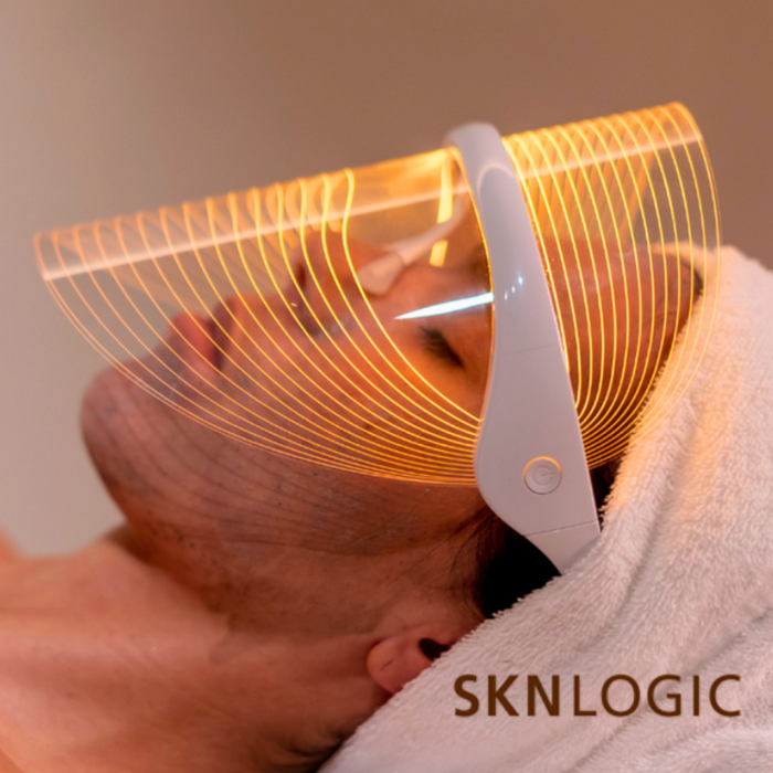 Person using a Sknlogic device on their head with a warm glow