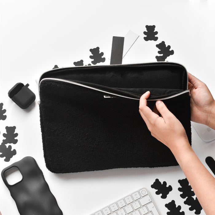 Hands holding a brown Teddy Baloo laptop sleeve on a desk with a keyboard, phone case, and black bear-shaped cutouts.