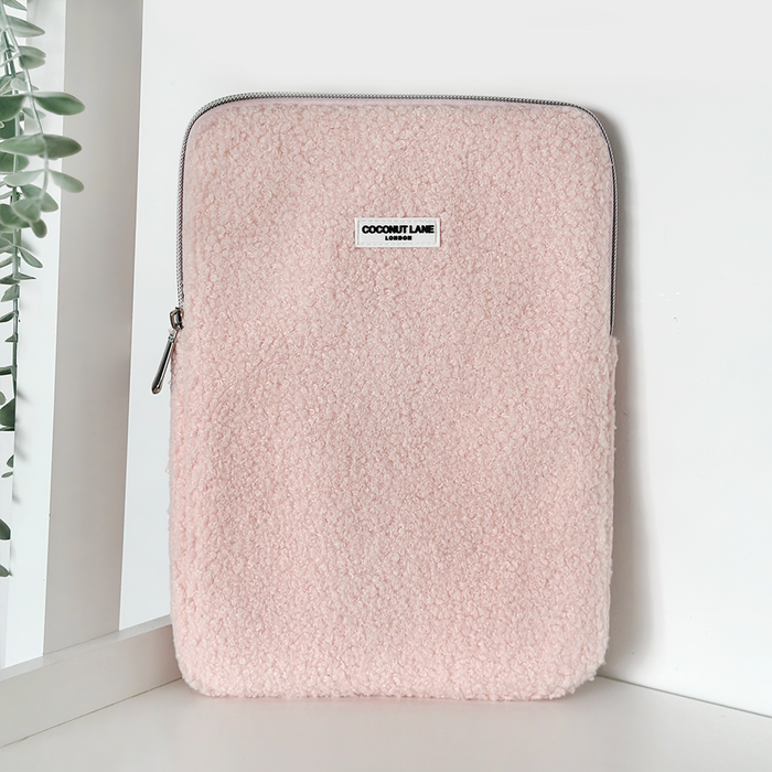 Light pink fuzzy Teddy Love-A-Lot iPad sleeve by Coconut Lane, standing upright next to a leafy plant.