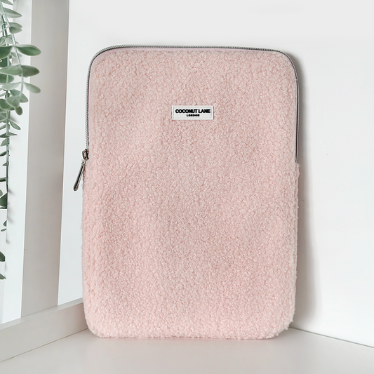Light pink fuzzy Teddy Love-A-Lot iPad sleeve by Coconut Lane, standing upright next to a leafy plant.