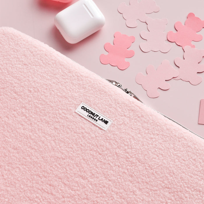Soft pink pouch, matching earbuds case, and teddy bear cutouts beside a pastel teddy-print laptop sleeve.