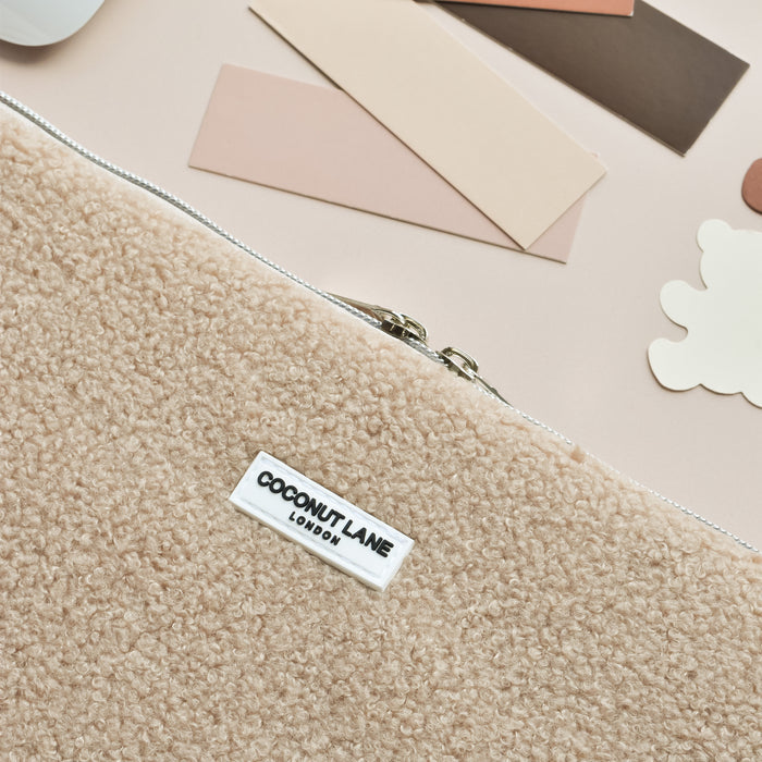 Beige fuzzy Coconut Lane Teddy Rupert laptop sleeve with zipper, displayed on a light surface alongside color swatches.