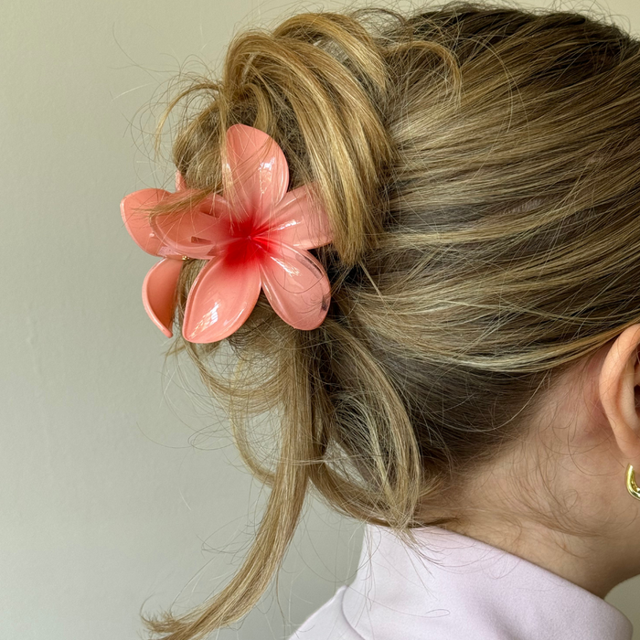 Blonde hair in a loose updo secured with a coral floral claw clip from Coconut Lane, viewed from behind.