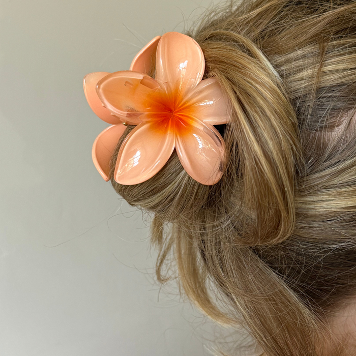 Coconut Lane Hibiscus Claw Clip in peach secures light brown hair styled in a bun.