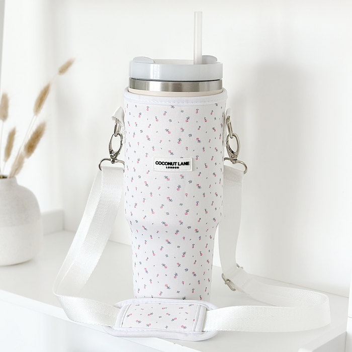 White Coconut Lane tumbler carry case with ditsy floral pattern, white mug, lid, and straw on a white shelf.
