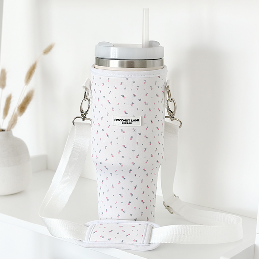 White Coconut Lane tumbler carry case with ditsy floral pattern, white mug, lid, and straw on a white shelf.