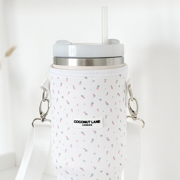White tumbler with lid and straw inside a white carry case with ditsy floral pattern, Coconut Lane branding visible.