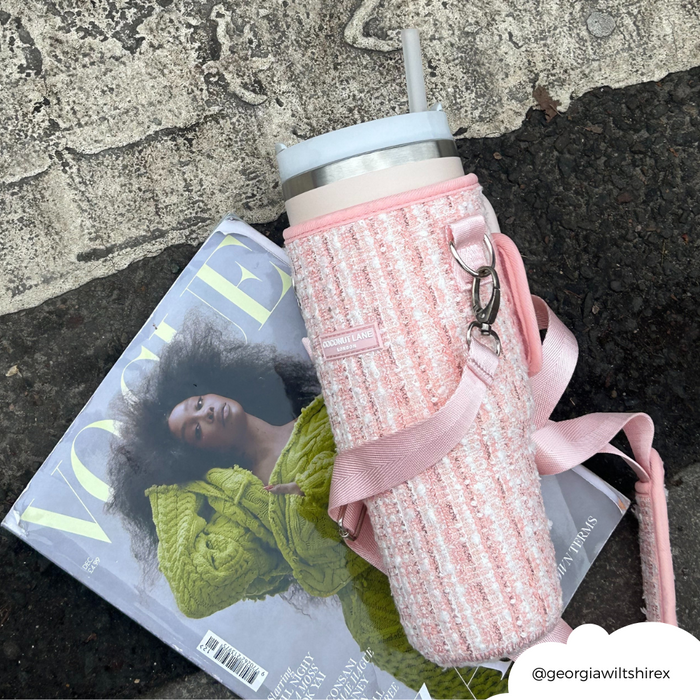 Pink textured tweed tumbler carry case with strap, by Coconut Lane, resting on a Vogue magazine.