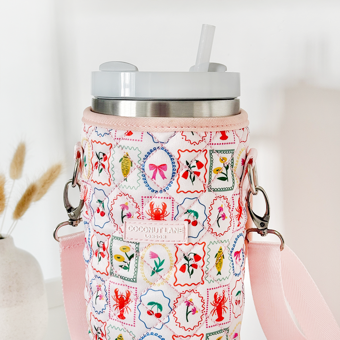 Stanley Quencher 40oz in a quilted Dolce Vita carry case with pink strap and lid, shown on a white surface.