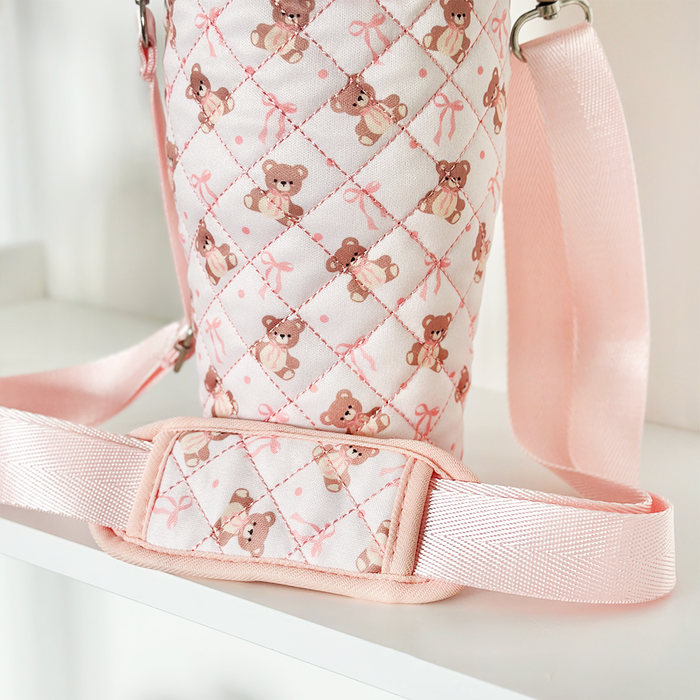 Pink quilted tumbler carry case with a wide strap, decorated with teddy bear and bow patterns.