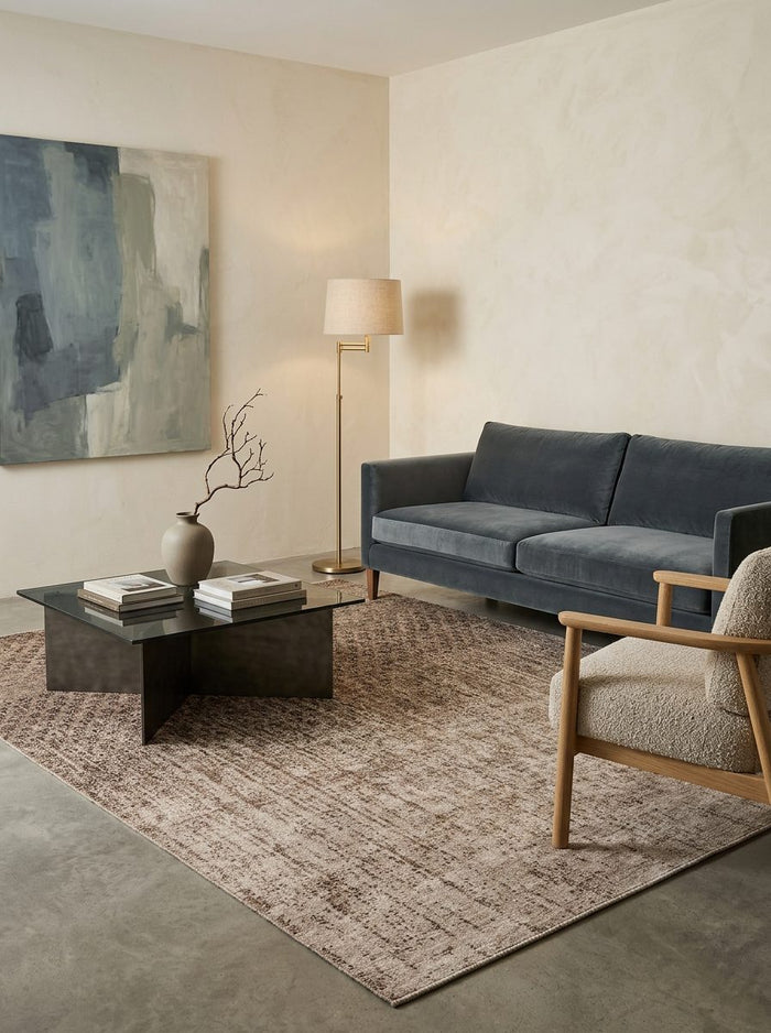 Brown and beige distressed-pattern rug in a modern living room with a dark blue sofa and glass coffee table.
