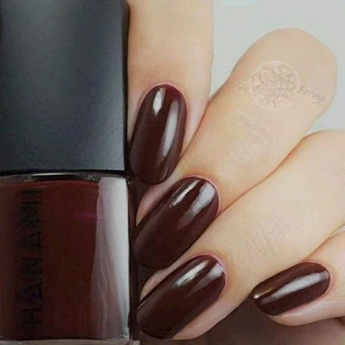 Nail polish bottle with a hand showing dark brown nails.